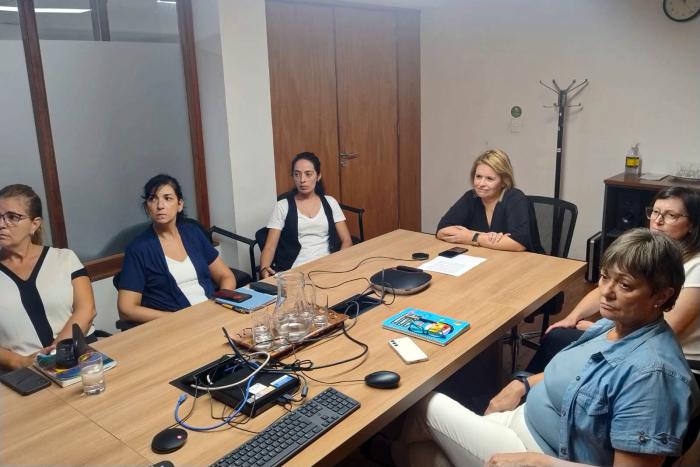 Reunión presencial y virtual sobre la temática Mujeres reunidas al rededor de una mesa