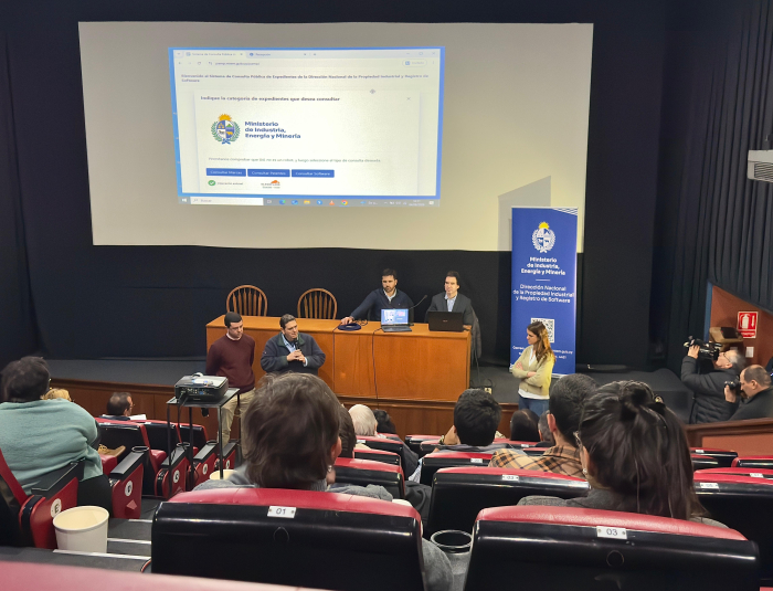 Taller de sensibilización sobre marcas y patentes. Foto: DNPI. Gente sentada mira una pantalla y 2 personas están sentadas detrás de una mesa