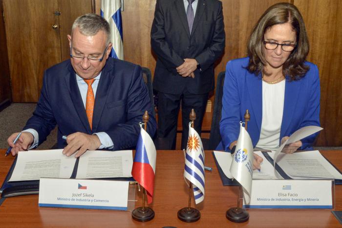 Ministra Facio y ministro Sikela firman el documento; detrás se ve el fragmento de un hombre de pie