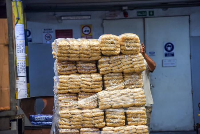 Pila de alimentos envasados; se ve la mano de una persona que los sostiene