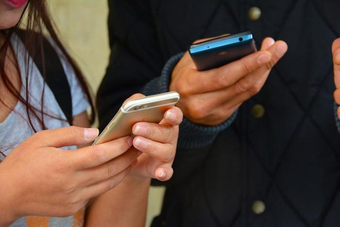 Manos de un hombre y una mujer con celulares