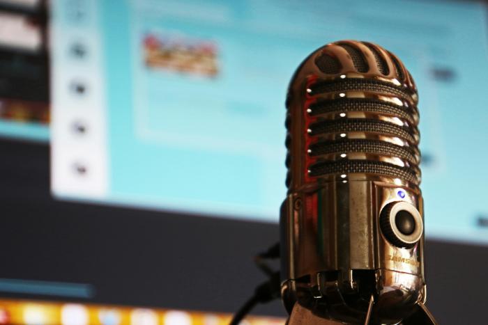 Los medios pueden inscribirse en el registro hasta el 10 de febrero de 2025 En primer plano, un micrófno; al fondo, una pantalla de computadora