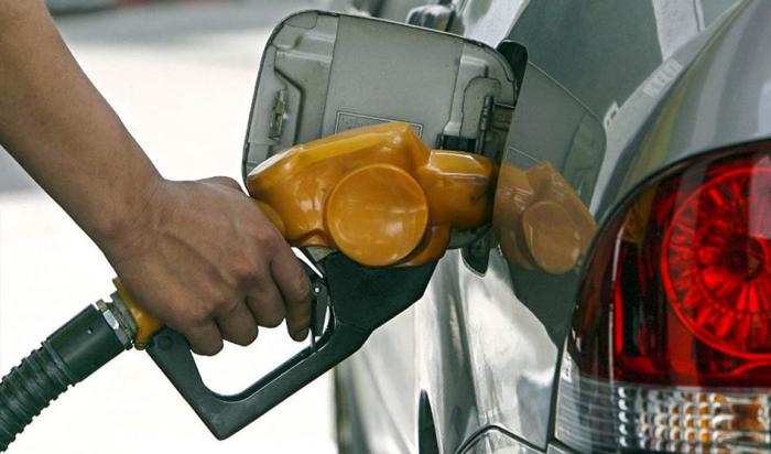 Mano cargando combustible en un auto plateado