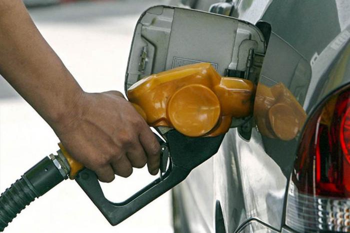 Mano con un surtidor de combustible, cargando un auto de color gris