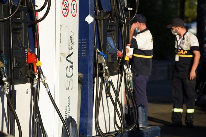 Dos trabajadores se ven junto a surtidores de combustibles