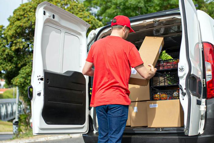 Trabajador postal haciendo el reparto de alimentos en su camioneta 