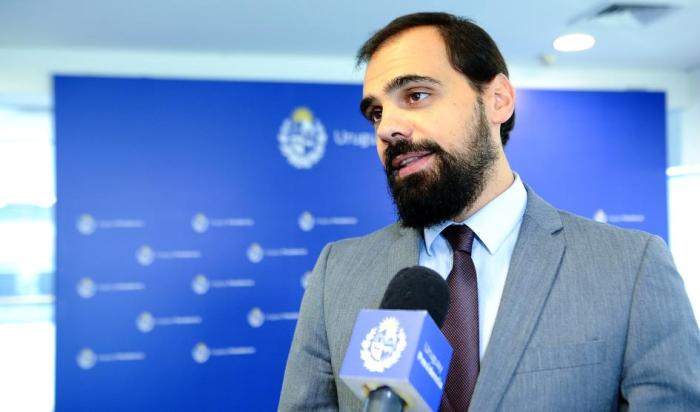 Director técnico de la Propiedad Industrial, Santiago Martínez Santiago Martínez habla ante un micrófono de Presidencia; detrás, banner del organismo