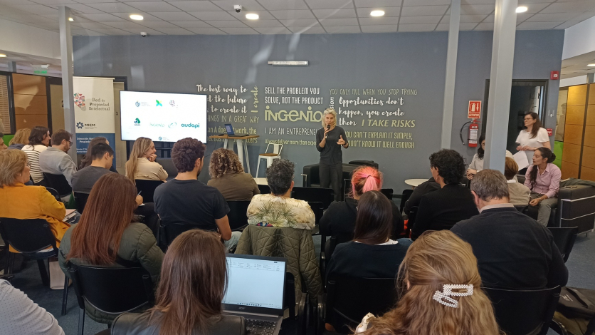Persona parada frente al publico asistente, sentado