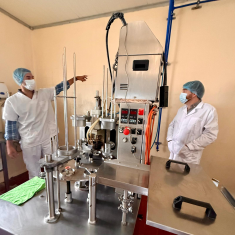 Personas con túnicas y tapabocas en planta industrial