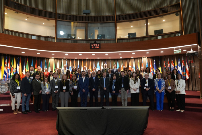 Todas las personas que participaron de la conferencia, paradas con las banderas de los países detrás