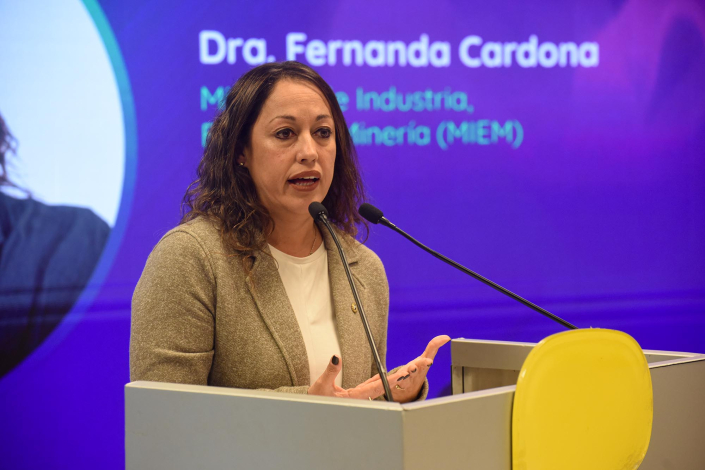 Cardona habla desde un atril; detrás se ve fragmento de pantalla con su nombre y cargo