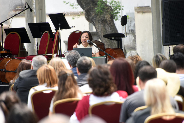 Al fondo, ministra Cardona habla desde un atril; de espaldas, mesa de autoridades; frente, público
