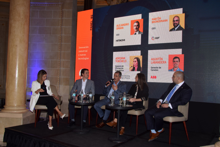 Panel de expertos reunidos en el escenario durante su exposición, acompañados por una entrevistadora