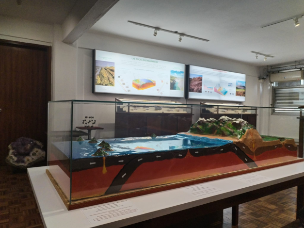 La imagen muestra una maqueta de la corteza terreste y carteles sobre rocas metamórficas