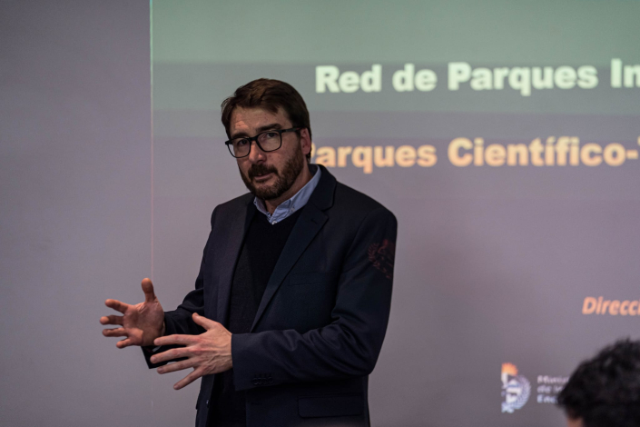Director Míguez habla de pie; detrás, una proyección