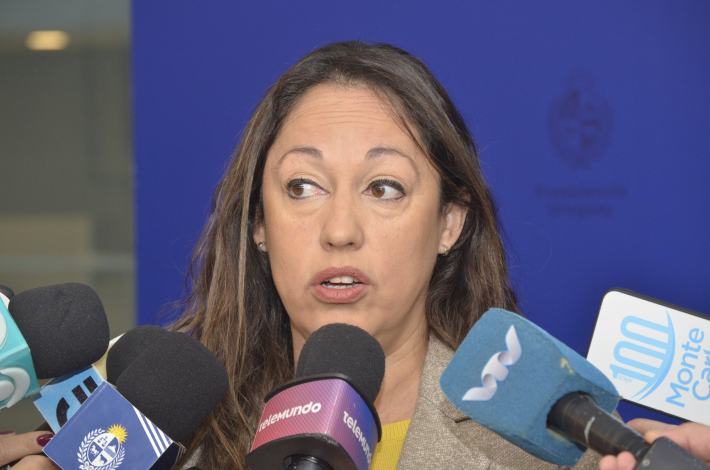 Ministra habla; alrededor, micrófonos