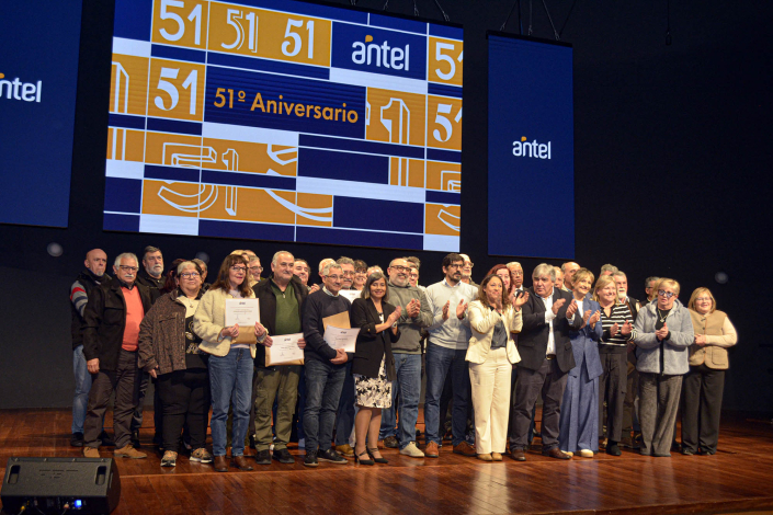 Personas sobre estrado. Ministra Cardona en el medio. Al fondo, banner institucional de Antel