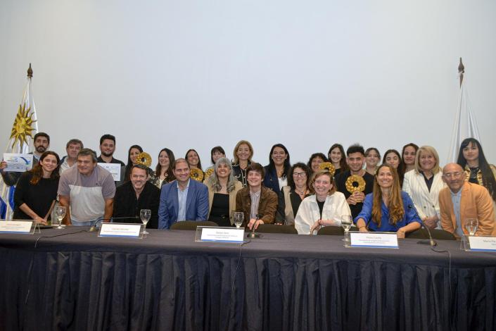 Ganadores del premio, con premios y diplomas, detrás de una mesa
