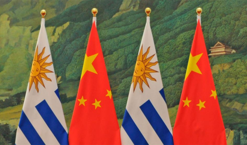 Dos banderas de Uruguay y China; al fondo, paisaje chino