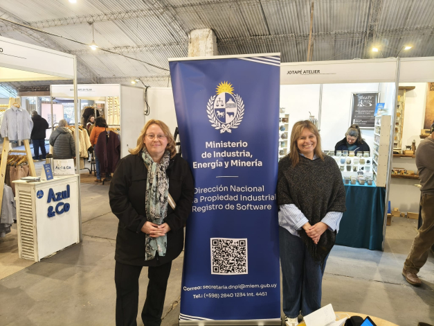Directoras Cidrás y Delor, a los lados de un banner del MIEM