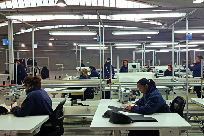 Mujeres cosen en mesas, en una planta industrial