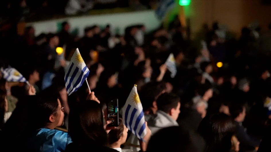 Jóvenes mirando el partido en el Auditorio Adela Reta Jóvenes con banderas de Uruguay en la mano
