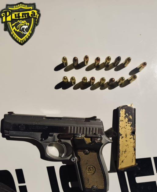 Pistola incautada con cargador y municiones alineadas sobre una mesa Pistola incautada con cargador y municiones alineadas sobre una mesa