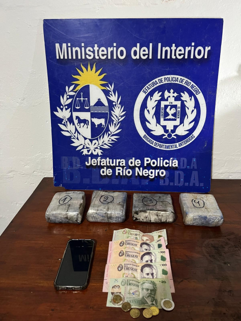 sobre una mesa cuatro paquetes, un celular y dinero