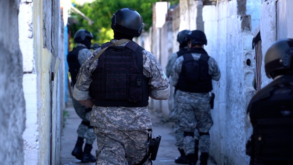 Policías uniformados de pixeleado dentro de un pasaje de espaldas.
