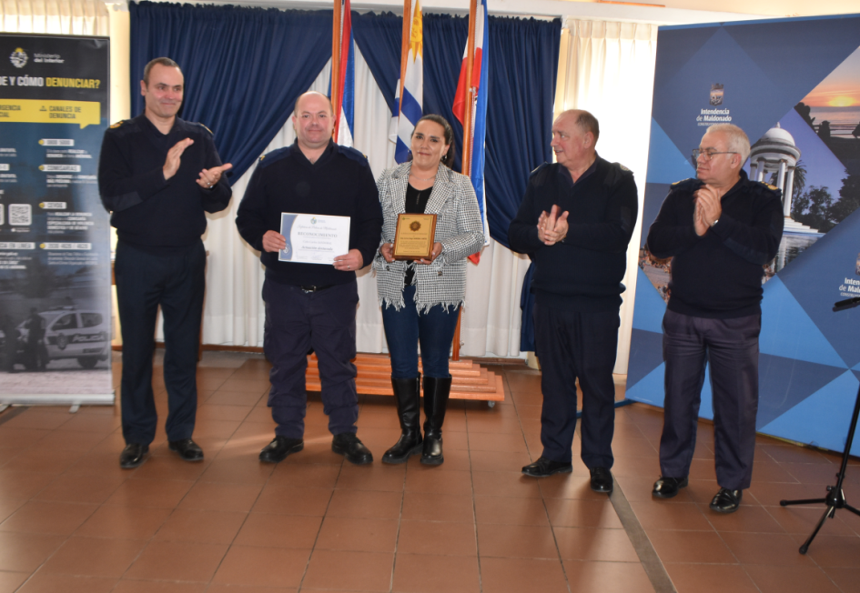 Reconocimiento a Cabo Sandobal Cinco personas paradas, algunas de ellas recibiendo un reconocimiento