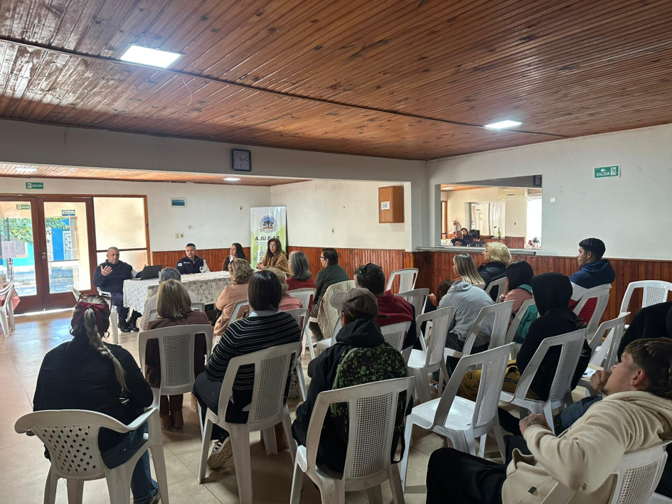 Charla informativa con vecinos con público sentado escuchando a expositores