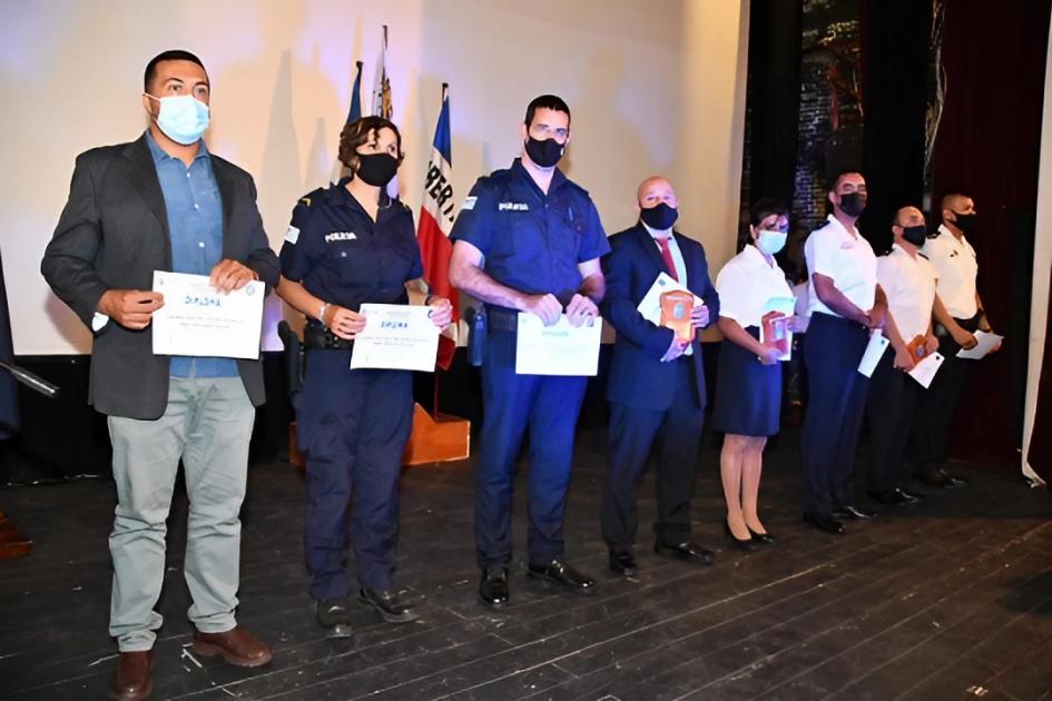 Acto de reconocimiento a policías destacados ocho policías parados mostrando los diplomas que recibieron en reconocimiento por su labor