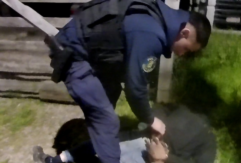 Policía con detenido esposado detenido esposado a la espalda por el policía que lo detuvo