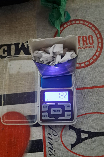 Estupefacientes envuelto en papel dentro de una caja de carton encima de una balanza de precision.