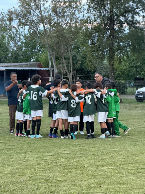 Equipo de fútbol infantil en círculo escuchando a su entrenador Reunion en el campo del equipo de fútbol.