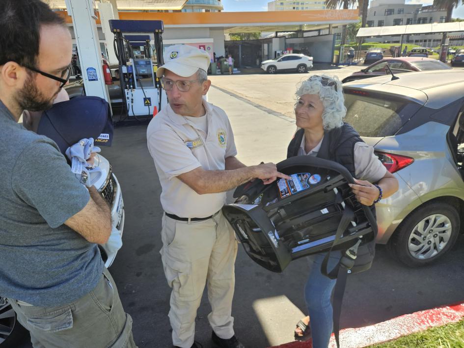 Funcionarios de Policía Caminera explicando a padre como ajustar los niveles del arnés del SRI Funcionarios de Policía Caminera explicando a padre como ajustar los niveles del arnés del SRI