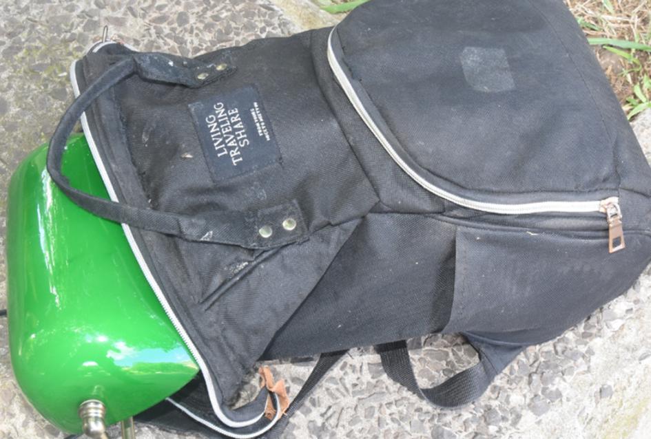 Foto de una mochila de color negro y en su interior una lámpara portátil de color verde. Foto de una mochila de color negro y en su interior una lámpara portátil de color verde.