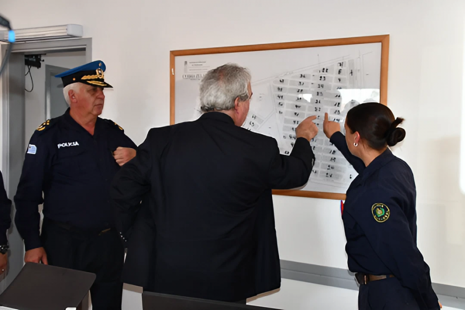 ministro del interior y funcionarios policiales observando un plano en la pared