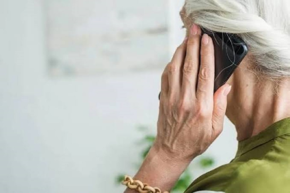 Imagen ilustrativa mujer aldulta con canas y buzo verde hablando por teléfono