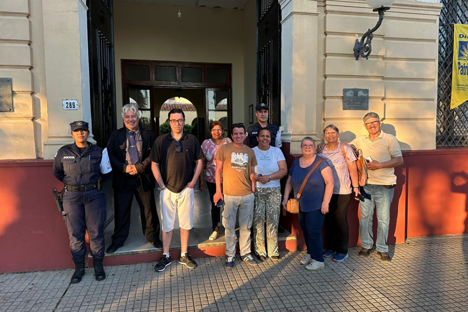 Personal de Prensa y de Policia Comunitaria de Jefatura junto a visitantes frente a Jefatura de Poli