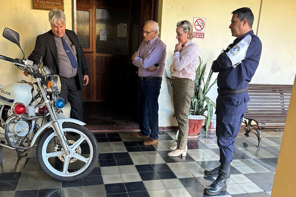 Personal de Prensa y de Policia Comunitaria de Jefatura mostrando motocileta en museo.