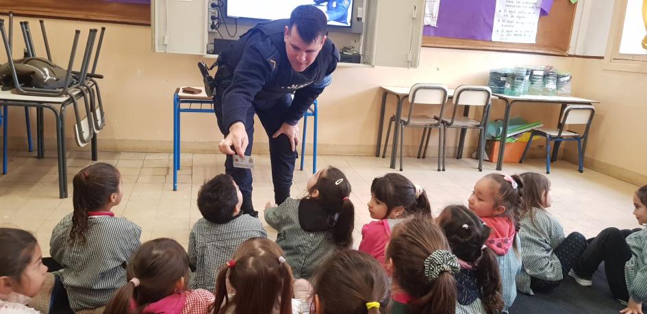 Policía comunitario con alumnos de jardín mostrando un documento Policía comunitario con alumnos de jardín mostrando un documento
