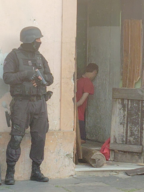 Policía custodiando escena con detenido