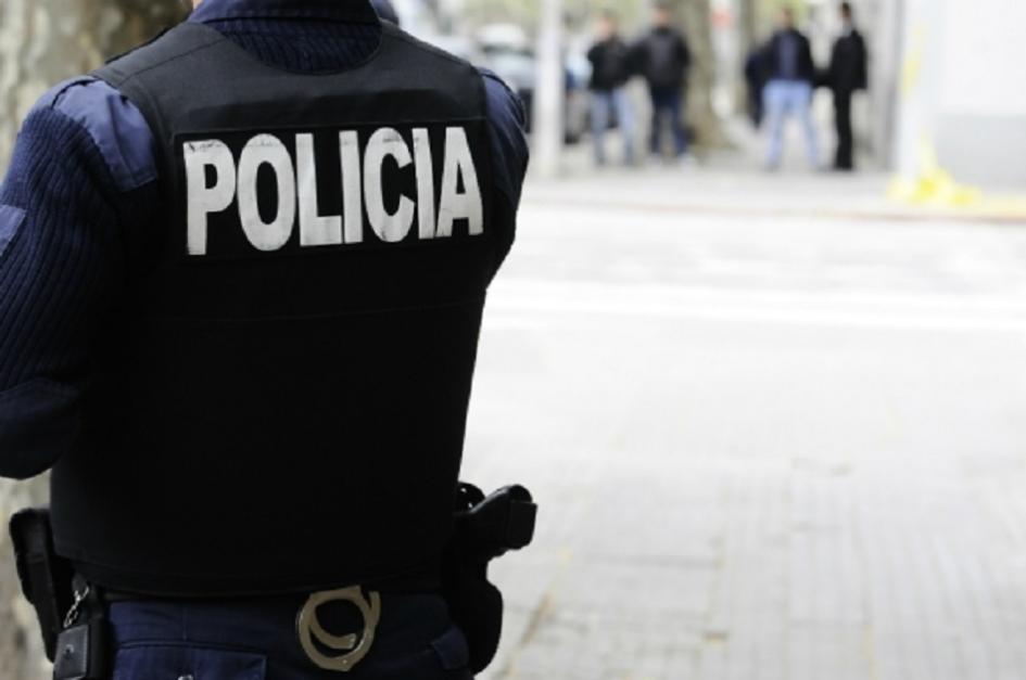 Policía de espalda y detenidos al fondo lejos Policía de espalda y detenidos al fondo lejos