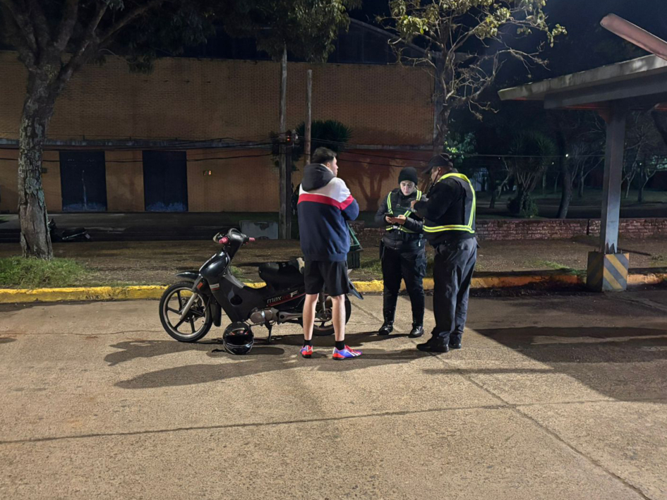 Control de un motciclista Policías realizan un control a una persona junto a una motocicleta durante la noche