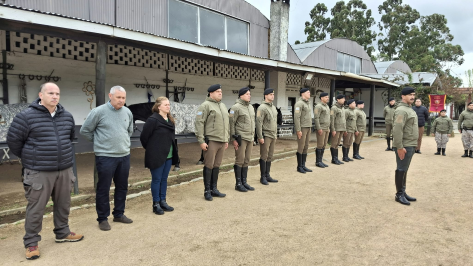 Formación policial cursantes e instructores Personal uniformado alineado de pie junto a instructores de civil y jefe de curso al frente.