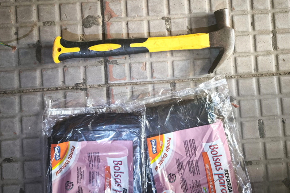Un martillo con dos paquetes de bolsas de residuos.