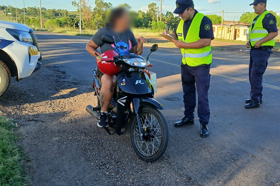 Una persona en moto siendo controlada por dos policías.