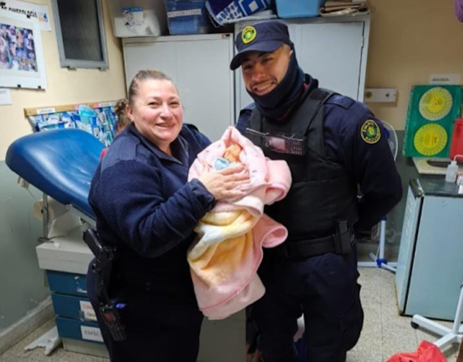 Una policía mujer y uno varón sosteniendo al recién nacido