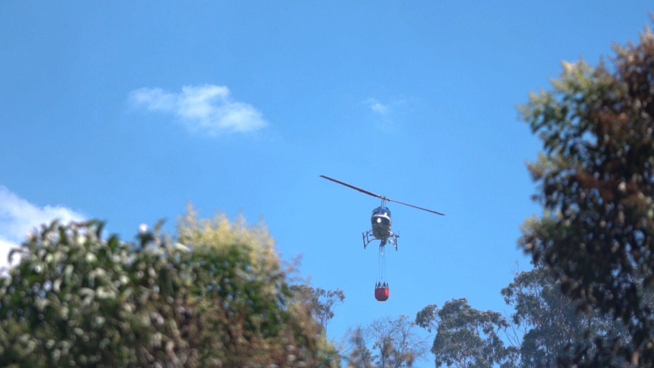 Helicóptero de Aviación con helibalde en foco de incendio Helicóptero de Aviación con helibalde en foco de incendio